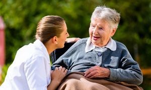 Nurse holding hands with senior woman in wheelchair